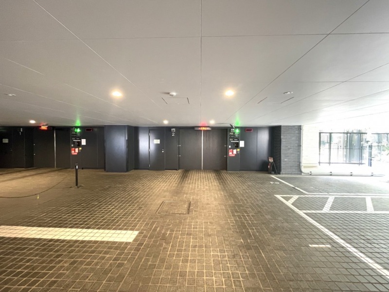 【駐車場】天候に左右されない屋内タイプで、複数基のシャッターと入出庫サインが整備され、効率的な運用が想定されています。エントランスから駐車場までがスムーズに繋がっており、雨天でも快適に移動できる設計でセキュリティーにも配慮されています。