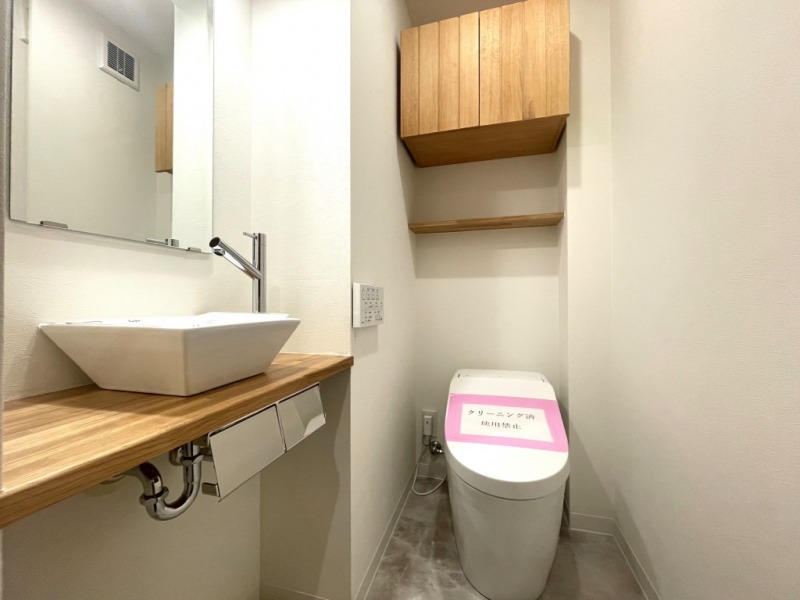 【トイレ】タンクレスですっきりとしたデザインのウォシュレット付きトイレです。吊戸棚収納やミラー付の便利な専用手洗いスペースが設けられています。