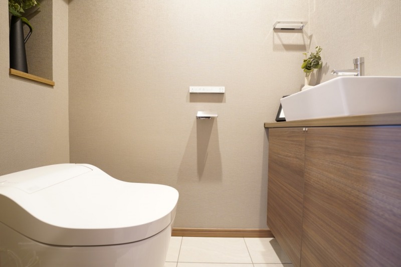 【トイレ】お手入れのしやすいタンクレスで、すっきりとしたデザインの温水洗浄機能付きトイレです。室内は清潔感があり落ち着く上質な空間です。トイレットペーパーなどが収納できる吊戸棚も設置されています。便利な専用手洗いスペースも設けられています。