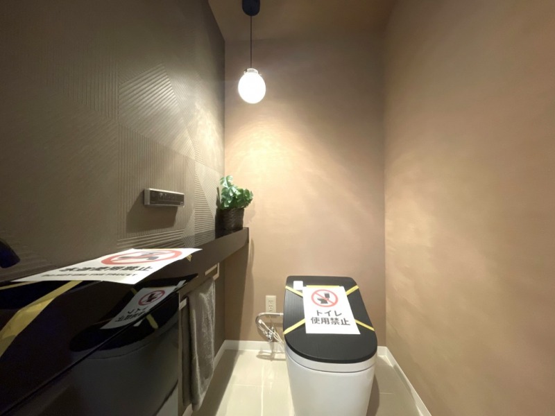 【1階トイレ】お手入れのしやすいタンクレスで、すっきりとしたデザインの温水洗浄機能付きトイレです。室内は清潔感があり落ち着く上質な空間です。カウンターと収納付きの便利な専用手洗いスペースも設けられています。
