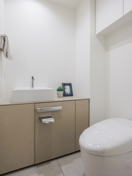 【トイレ】お手入れのしやすいタンクレスで、すっきりとしたデザインの温水洗浄機能付きトイレです。室内は清潔感があり落ち着く上質な空間です。トイレットペーパーなどが収納できる吊戸棚も設置されています。カウンター付きの便利な専用手洗いスペースも設けられています。