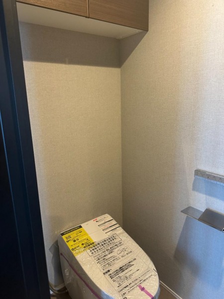 【トイレ】お手入れのしやすいタンクレスで、すっきりとしたデザインの温水洗浄機能付きトイレです。室内は清潔感があり落ち着く上質な空間です。トイレットペーパーなどが収納できる吊戸棚も設置されています。便利な専用手洗いスペースも設けられています。