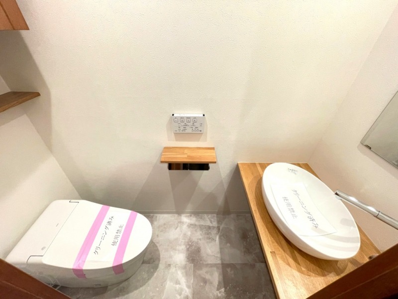 【トイレ】お手入れのしやすいタンクレスで、すっきりとしたデザインの温水洗浄機能付きトイレです。室内は清潔感があり落ち着く上質な空間です。トイレットペーパーなどが収納できる吊戸棚も設置されています。ミラー付きの便利な専用手洗いスペースも設けられています。