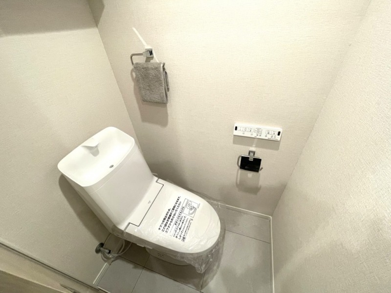 【トイレ】室内はホワイトを基調としていて清潔感があり、すっきりとした落ち着ける空間です。トイレもうれしい温水洗浄機能付きです。吊戸棚も設置されており、トイレットペーパーなどが収納できます。