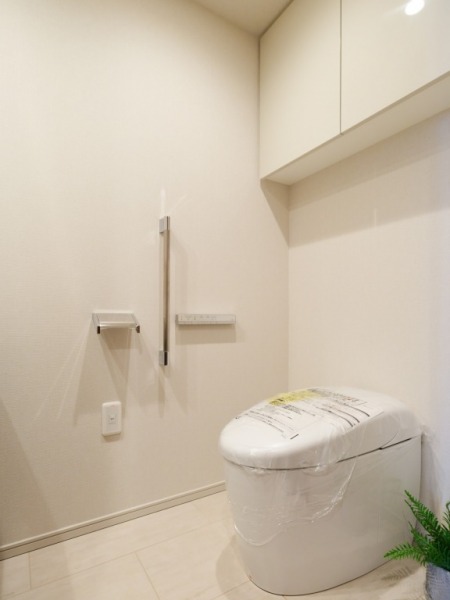 【トイレ】お手入れのしやすいタンクレスで、すっきりとしたデザインの温水洗浄機能付きトイレです。室内はホワイトを基調とし清潔感があり落ち着く上質な空間です。トイレットペーパーなどが収納できる吊戸棚も設置されています。カウンター付きの便利な専用手洗いスペースも設けられています。