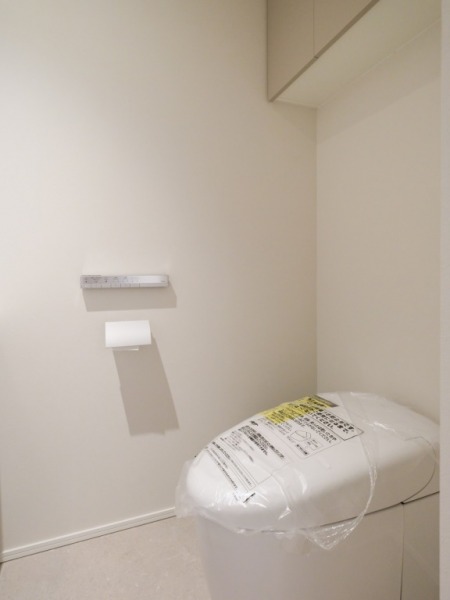 【トイレ】お手入れのしやすいタンクレスで、すっきりとしたデザインの温水洗浄機能付きトイレです。室内は清潔感があり落ち着く上質な空間です。トイレットペーパーなどが収納できる吊戸棚も設置されています。カウンター付きの便利な専用手洗いスペースも設けられています。