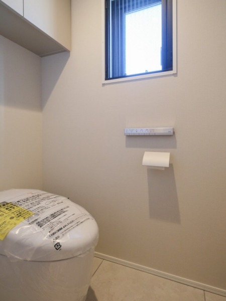 【トイレ】お手入れのしやすいタンクレスで、すっきりとしたデザインの温水洗浄機能付きトイレです。室内は清潔感があり落ち着く上質な空間です。トイレットペーパーなどが収納できる吊戸棚も設置されています。便利な専用手洗いスペースも設けられています。また窓があるので明るく、こもりがちな臭いも換気ができて快適です。
