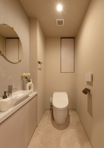 【トイレ】お手入れのしやすいタンクレスで、すっきりとしたデザインの温水洗浄機能付きトイレです。室内は清潔感があり落ち着く上質な空間です。トイレットペーパーなどが収納できる吊戸棚も設置されています。ミラーとカウンター付きの便利な専用手洗いスペースも設けられています。