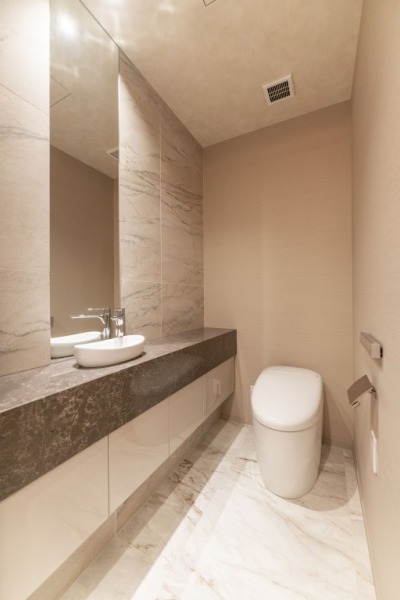 【トイレ】お手入れのしやすいタンクレスで、すっきりとしたデザインの温水洗浄機能付きトイレです。室内は落ち着く上質な空間です。カウンターとミラー付きの便利な専用手洗いスペースも設けられています。