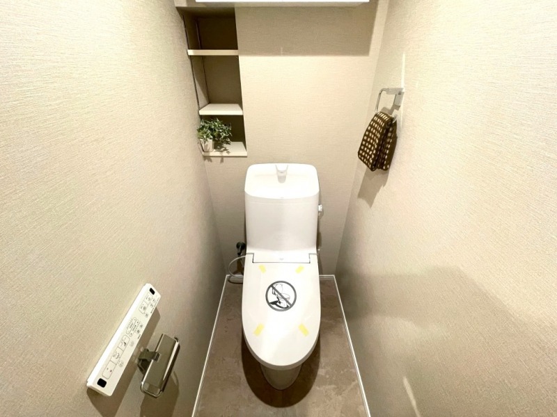 【トイレ】すっきりとしたデザインで清潔感があり、落ち着ける空間です。トイレもうれしい洗浄機能付きです。戸棚も設置されており、トイレットペーパーなどが収納できます。
