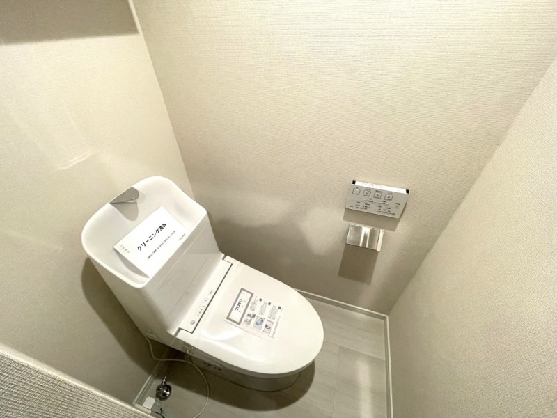 【トイレ】すっきりとしたデザインで清潔感があり、落ち着ける空間です。トイレもうれしい洗浄機能付きです。吊戸棚も設置されており、トイレットペーパーなどが収納できます。