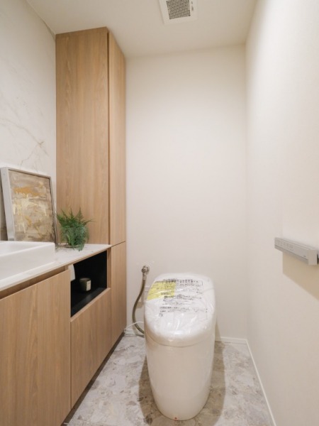 【トイレ】お手入れのしやすいタンクレスで、すっきりとしたデザインの温水洗浄機能付きトイレです。室内は清潔感があり落ち着く上質な空間です。収納とカウンター付きの便利な専用手洗いスペースも設けられています。