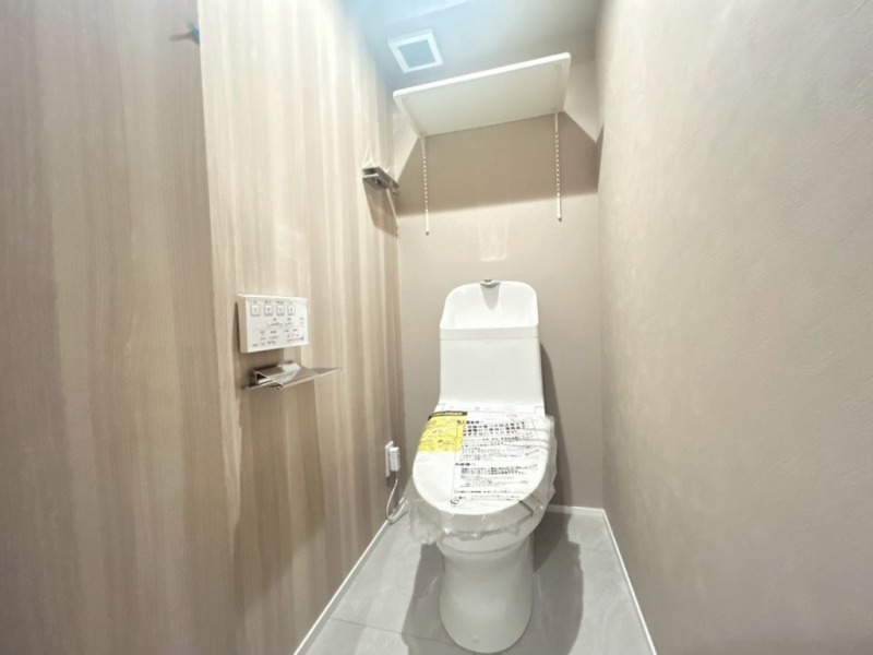 【トイレ】すっきりとしたデザインで清潔感があり、落ち着ける空間です。トイレもうれしい洗浄機能付きです。吊棚も設置されており、トイレットペーパーなどが収納できます。
