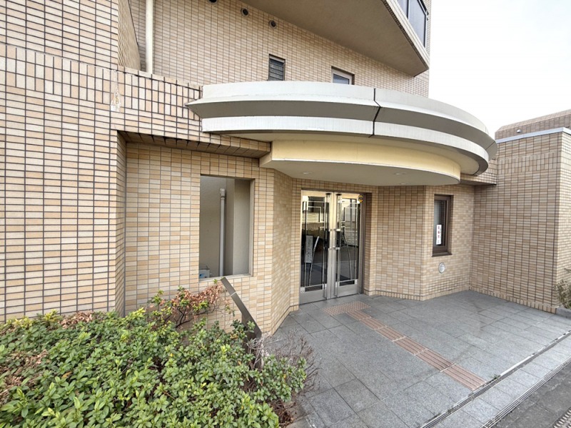 【エントランス】半円のキャノピーが印象的な、重厚で上質感を備えたエントランスが、住まう方を静かに迎えます。オートロックなどの基本的なセキュリティを備え、不在時に便利な宅配ボックスも設置されています。