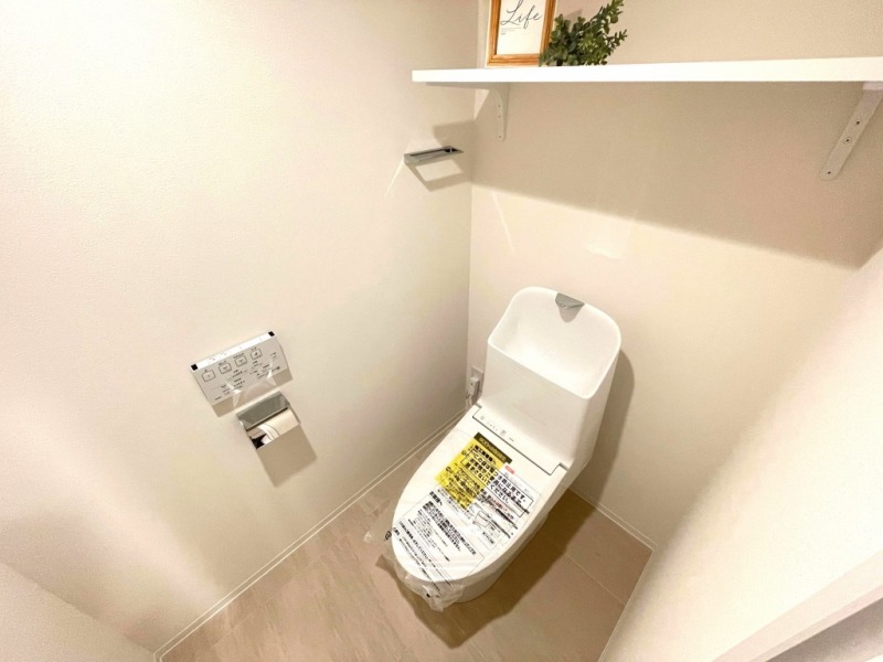 【トイレ】すっきりとしたデザインで清潔感があり、落ち着ける空間です。トイレもうれしい洗浄機能付きです。戸棚も設置されており、トイレットペーパーなどが収納できます。