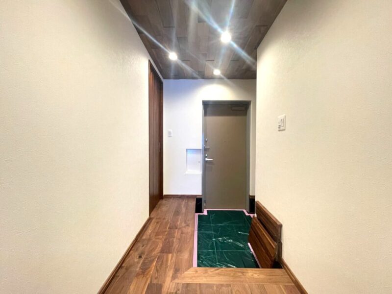 【玄関】玄関は広めにとられており、天井やフローリングも天然無垢材を使用し、ブラックの石目タイルフロアで上品な空間となっています。玄関横には大容量のシューズインクローゼットを備え、シューズもたっぷり、ベビーカーや傘立ても収納でき、玄関フロアもすっきりご利用頂けます。