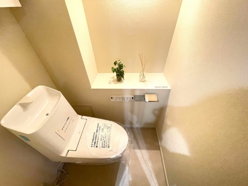 【トイレ】すっきりとしたデザインで清潔感のある空間です。トイレもうれしい洗浄機能付きです。吊戸棚も設置されており、トイレットペーパーなどが収納できます。