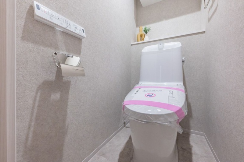 【トイレ】すっきりとしたデザインで清潔感があり、落ち着ける空間です。トイレもうれしい洗浄機能付きです。吊戸棚も設置されており、トイレットペーパーなどが収納できます。