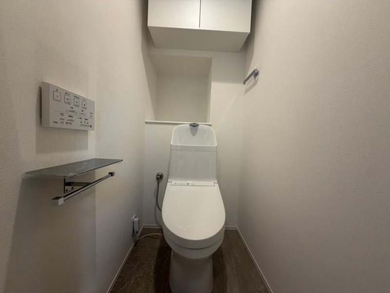 【トイレ】すっきりとしたデザインで清潔感があり、落ち着ける空間です。トイレもうれしい洗浄機能付きです。吊戸棚も設置されており、トイレットペーパーなどが収納できます。