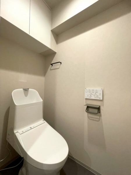 【トイレ】洗面台横のトイレはすっきりとしたデザインで清潔感がある空間です。トイレもうれしい洗浄機能付きです。吊戸棚も設置されており、トイレットペーパーなどが収納できます。