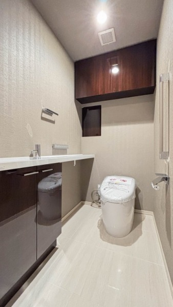 【トイレ】タンクレスですっきりとしたデザインのウォシュレット付きトイレです。お掃除の負担が軽減される機能も付いています。室内は清潔感があり落ち着ける上質な空間です。吊戸棚付きでトイレットペーパーなどの消耗品の収納ができます。カウンター付きの便利な専用手洗いスペースも付いています。