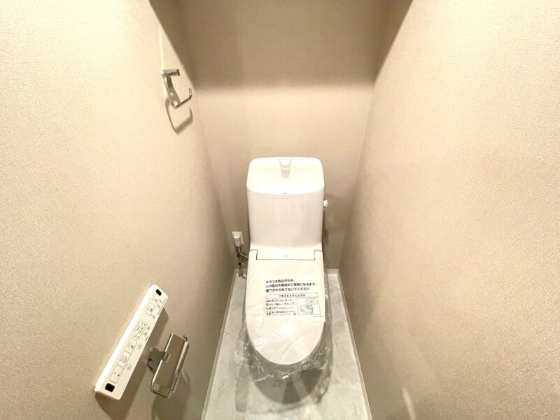 【トイレ】すっきりとしたデザインで清潔感があり、落ち着ける空間です。トイレもうれしい洗浄機能付きです。吊戸棚も設置されており、トイレットペーパーなどが収納できます。