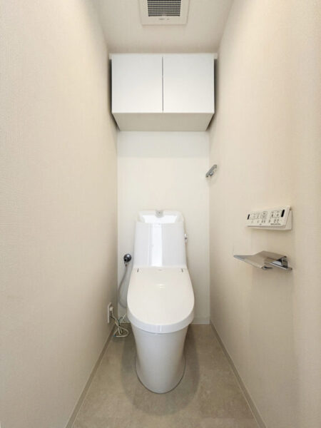 【トイレ】すっきりとしたデザインで清潔感があり、落ち着ける空間です。トイレもうれしい洗浄機能付きです。吊戸棚も設置されており、トイレットペーパーなどが収納できます。