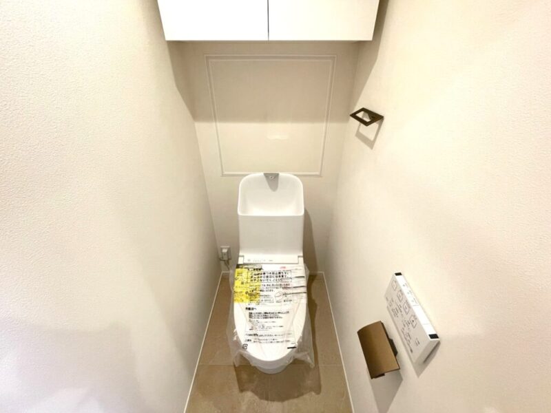 【トイレ】室内はホワイトを基調としていて清潔感があり、すっきりとした落ち着ける空間。トイレは温水洗浄機能付きです。吊戸棚も設置されており、トイレットペーパーなどが収納できます。