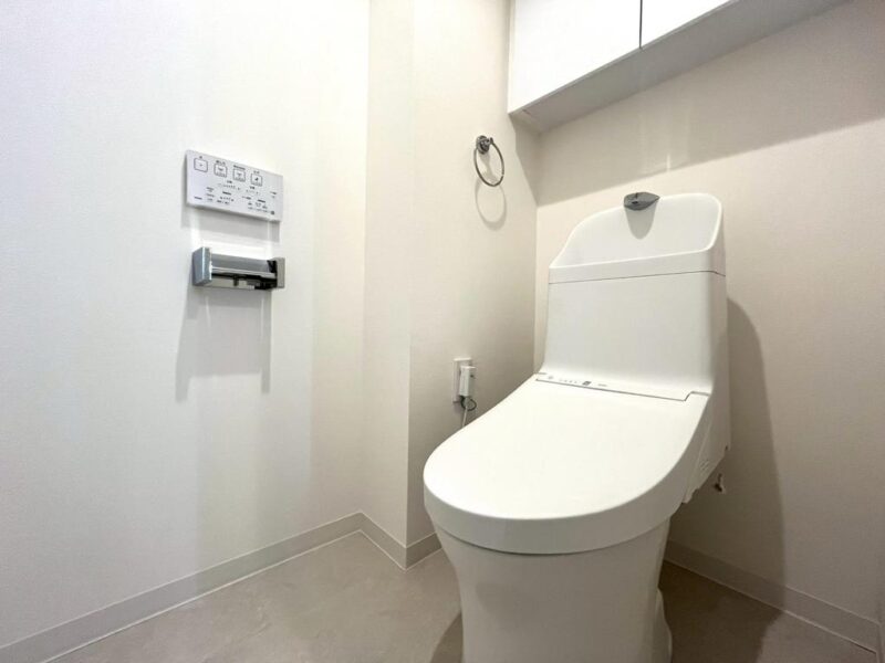 【トイレ】すっきりとしたデザインで清潔感があり、落ち着ける空間。トイレは温水洗浄機能付きです。吊戸棚も設置されており、トイレットペーパーなどが収納できます。