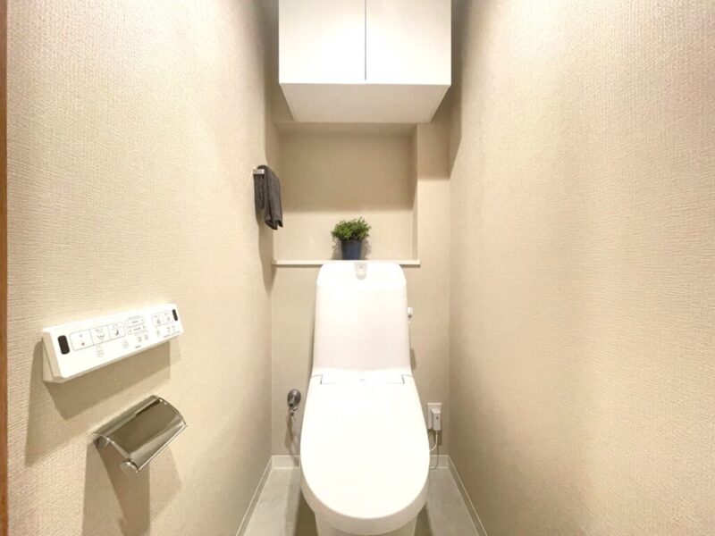 【トイレ】すっきりとしたデザインで清潔感があり、落ち着ける空間です。トイレもうれしい洗浄機能付きです。吊戸棚も設置されており、トイレットペーパーなどが収納できます。