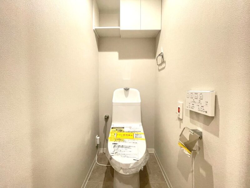 【トイレ】室内はホワイトを基調としていて清潔感があり、すっきりとした落ち着ける空間です。トイレもうれしい温水洗浄機能付きです。吊戸棚も設置されており、トイレットペーパーなどが収納できます。