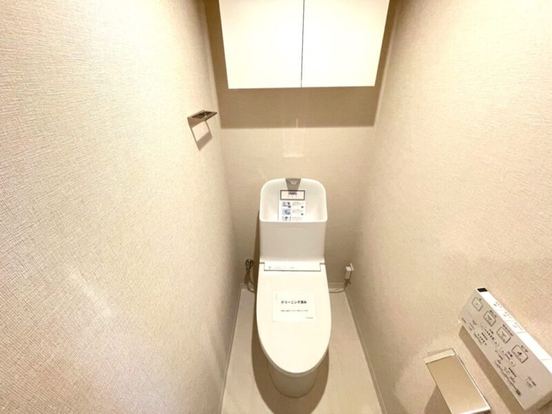 【トイレ】すっきりとしたデザインで清潔感があり、落ち着ける空間。トイレは温水洗浄機能付きです。吊戸棚も設置されており、トイレットペーパーなどが収納できます。