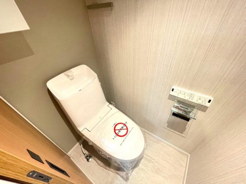 【トイレ】すっきりとしたデザインで清潔感があり、落ち着ける空間。トイレは温水洗浄機能付きです。吊戸棚も設置されており、トイレットペーパーなどが収納できます。