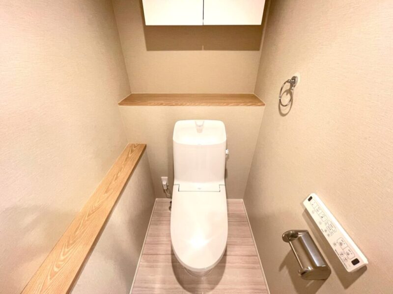 【トイレ】室内はホワイトを基調としていて清潔感があり、すっきりとした落ち着ける空間。トイレは温水洗浄機能付きです。吊戸棚も設置されており、トイレットペーパーなどが収納できます。