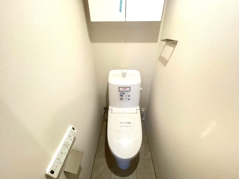 【トイレ】すっきりとしたデザインで清潔感があり、落ち着ける空間。トイレは温水洗浄機能付きです。吊戸棚も設置されており、トイレットペーパーなどが収納できます。