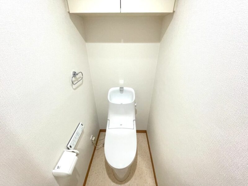 【トイレ】室内はホワイトを基調としていて清潔感があり、すっきりとした落ち着ける空間。トイレは温水洗浄機能付きです。吊戸棚も設置されており、トイレットペーパーなどが収納できます。