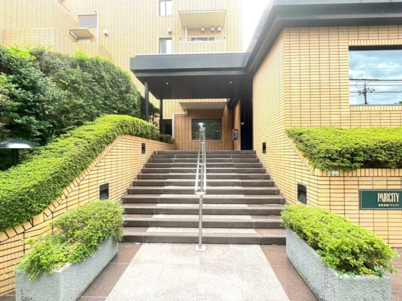 【エントランス】豊かな植栽と落ち着いた外観が迎えるエントランス。邸宅感のあるアプローチが、日常に上質な雰囲気を添えます。エントランスのオートロックをはじめ、防犯面に配慮した共用設備を備え、都心での暮らしを安心して支える住まいです。