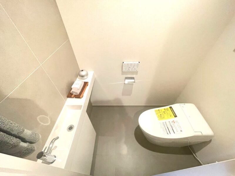 【トイレ】お手入れのしやすいタンクレスで、すっきりとしたデザインの温水洗浄機能付きトイレ。室内は清潔感があり落ち着く上質な空間です。カウンター付きの便利な専用手洗いスペースも設けられています。