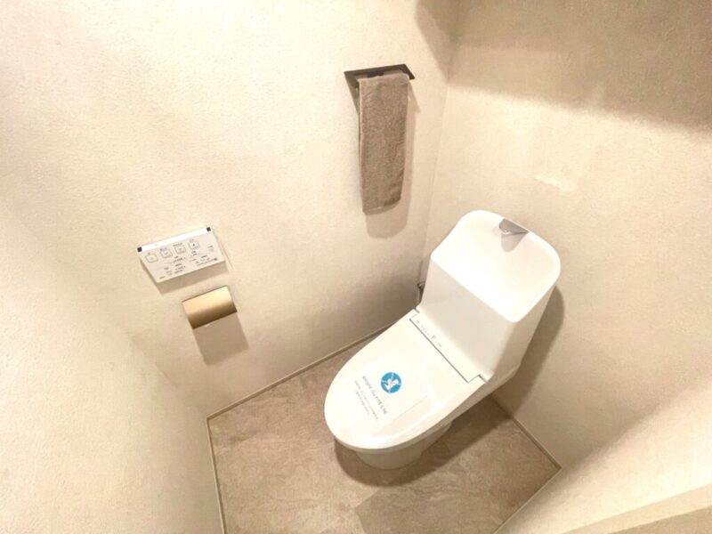 【トイレ】室内はホワイトを基調としていて清潔感があり、すっきりとした落ち着ける空間。トイレは温水洗浄機能付きです。吊戸棚も設置されており、トイレットペーパーなどが収納できます。