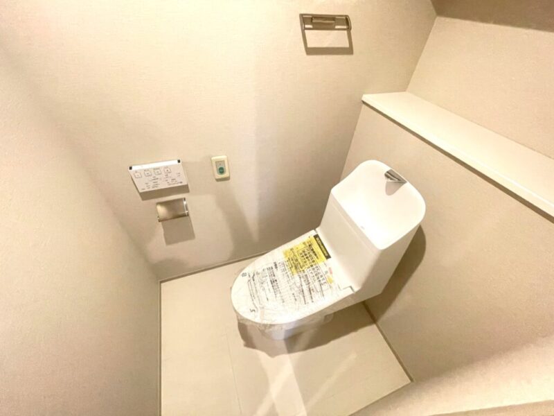 【トイレ】室内はホワイトを基調としていて清潔感があり、すっきりとした落ち着ける空間。トイレは温水洗浄機能付きです。吊戸棚も設置されており、トイレットペーパーなどが収納できます。