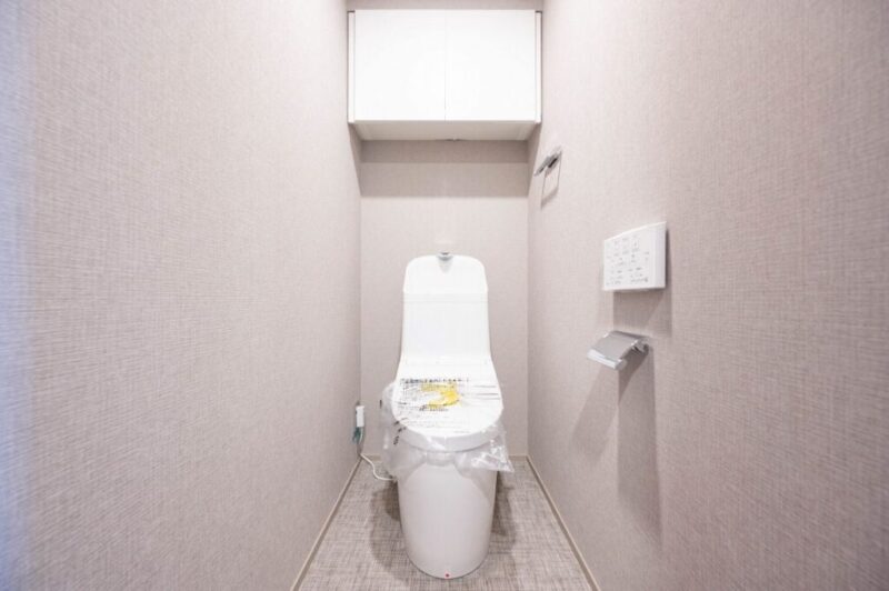 【トイレ】すっきりとしたデザインで清潔感があり、落ち着ける空間。トイレは温水洗浄機能付きです。吊戸棚も設置されており、トイレットペーパーなどが収納できます。