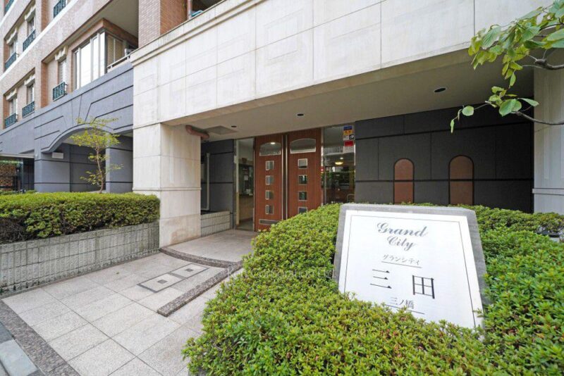 【エントランス】落ち着いた色調でまとめられたエントランスが、住まいの品格を演出。植栽と建物が美しく調和し、住まいへと心地よく誘います。オートロックや防犯カメラなどを備え、日々の暮らしに安心感をプラス。宅配ボックスも設置され、外出の多い都心生活を快適にサポートします。