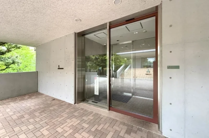 【エントランス】緑に囲まれたアプローチが、上質な住まいの第一印象を演出。大きなガラス貼りの開放感のあるエントランスです。安心のオートロックシステムに加え、防犯カメラを複数配置。宅配ボックス完備で、利便性と安全性を両立しています。