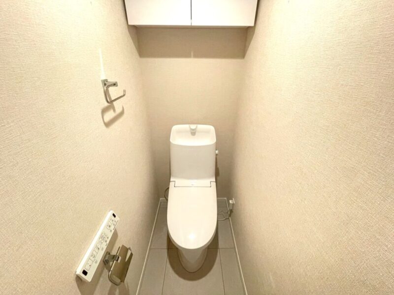 【トイレ】すっきりとしたデザインで清潔感があり、落ち着ける空間。トイレは温水洗浄機能付きです。吊戸棚も設置されており、トイレットペーパーなどが収納できます。