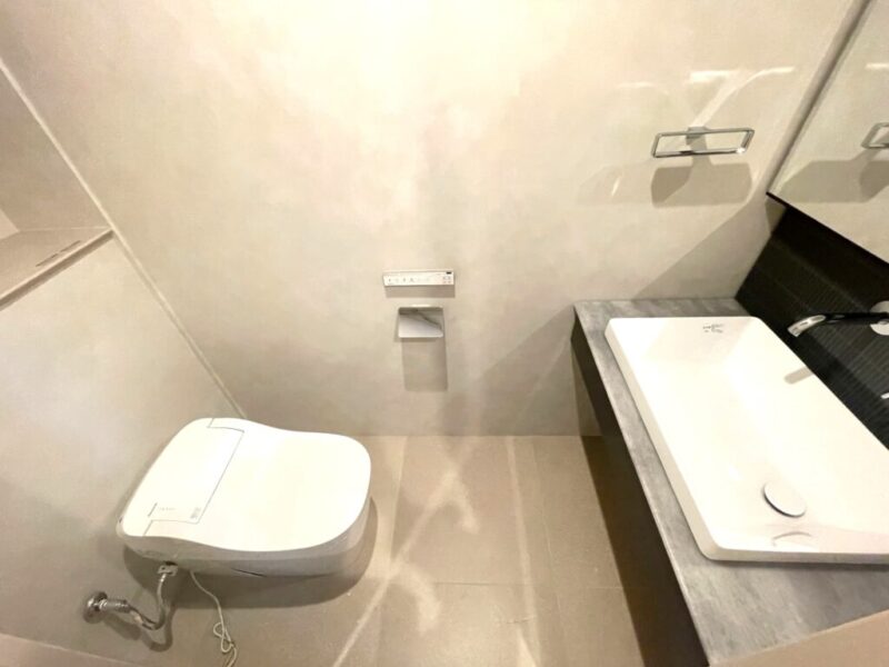 【トイレ】お手入れのしやすいタンクレスのすっきりとしたデザインの温水洗浄機能付きトイレ。室内は清潔感があり落ち着く上質な空間です。トイレットペーパーなどが収納できる吊戸棚を備え、便利な専用手洗いスペースも設けられています。