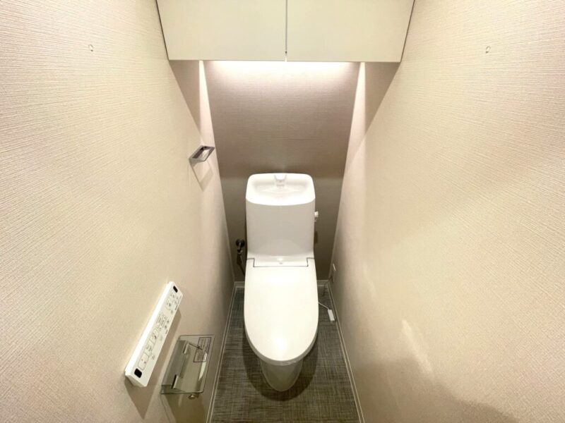 【トイレ】すっきりとしたデザインで清潔感があり、落ち着ける空間。トイレは温水洗浄機能付きです。吊戸棚も設置されており、トイレットペーパーなどが収納できます。